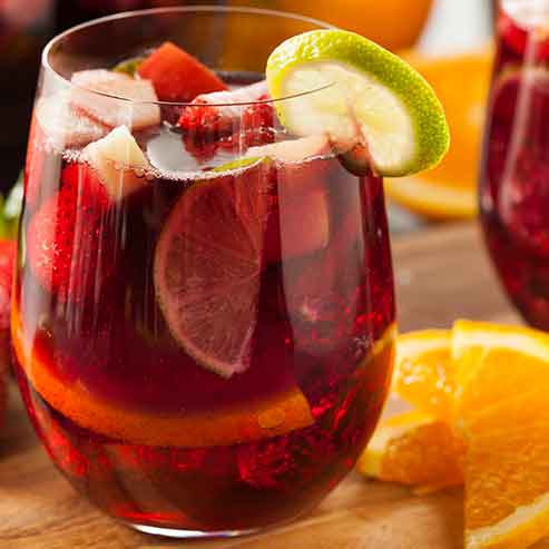 Glass of zero alcohol red wine sangria with limes, strawberries and oranges