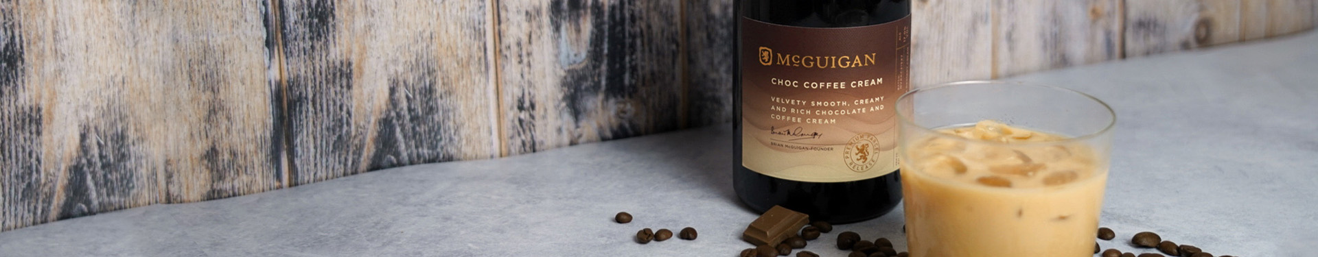 Bottle of and glass of McGuigan Choco Coffee Cream against a wooden wall