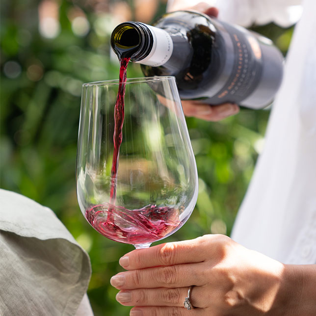 Woman pouring MuGuigan Mastercraft shiraz into a glass outdoors