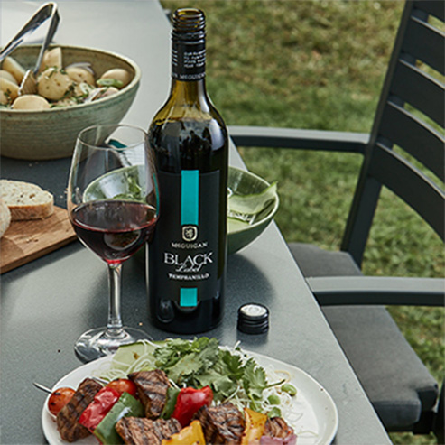 Glass and bottle of McGuigan Black Label Tempranillo with potatoes, salad and sourdough bread