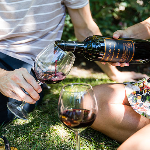 Individuals pouring McGuigan shiraz with watermelon salad and potatoes