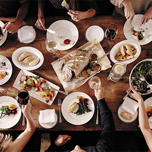 Individuals dining with fish, wine, potatoes and salad