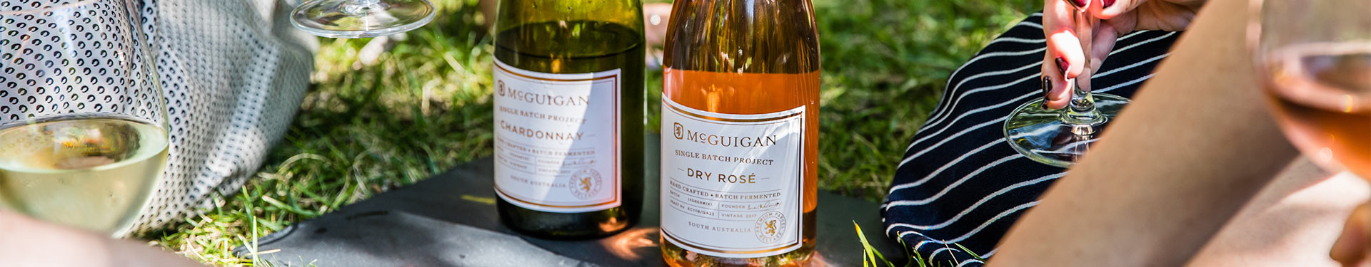 Women enjoying a bottle of Single Batch Project Rose and Sauvignon Blanc on a picnic blanket in an outdoor picnic setting.