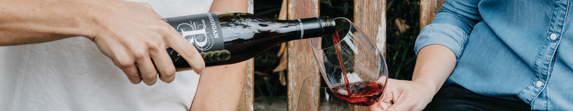 Man pouring glass of McGuigan Merlot Into a glass for a women outdoors